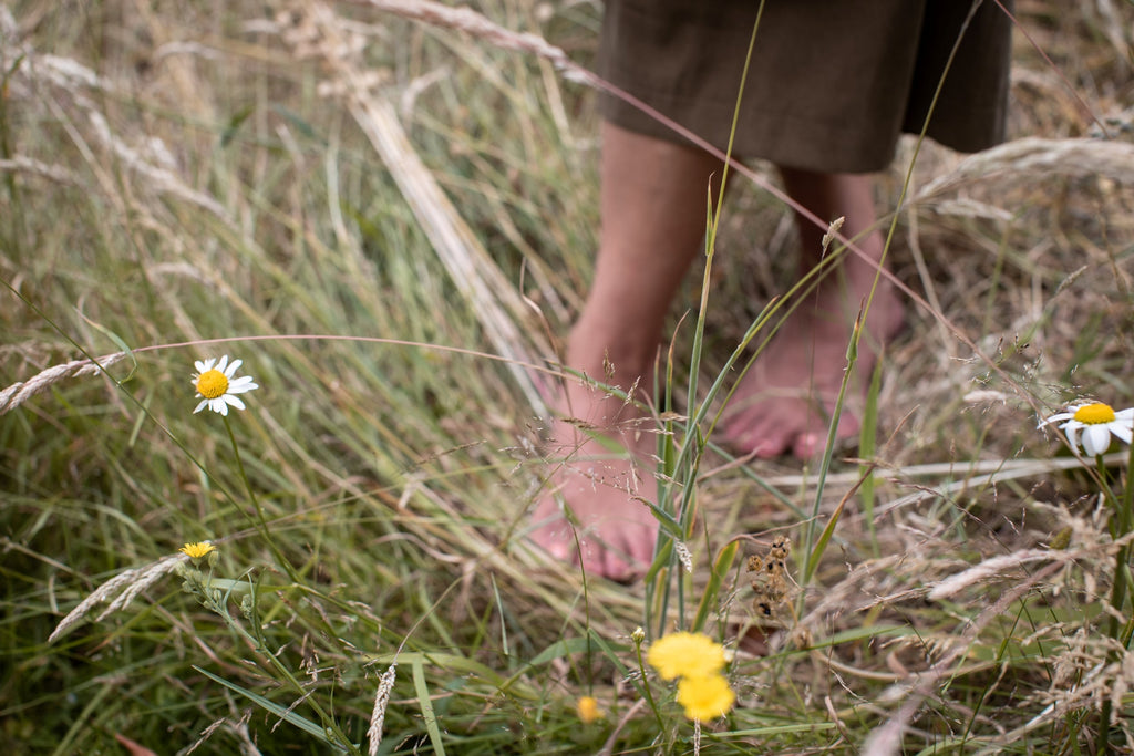 Bare foot asian women walking through long grass, skincare inspired by restoration and nutrition.