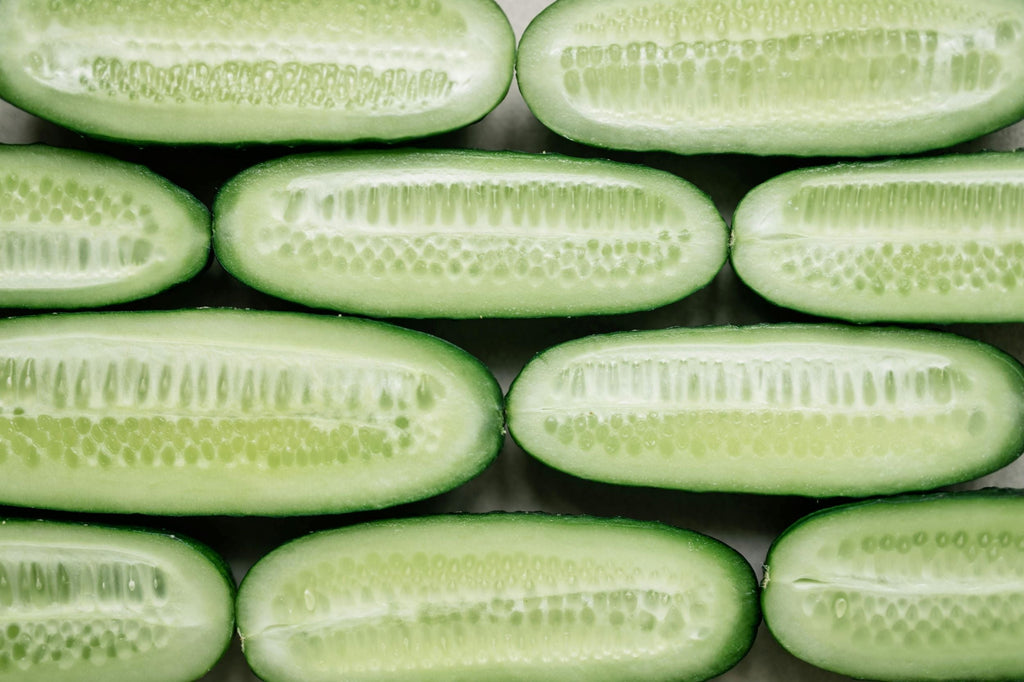 A brick wall effect of small cucumbers sliced in half with flesh and seeds showing