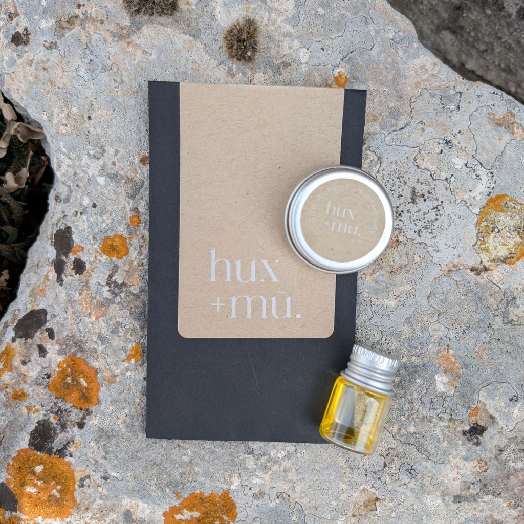 Small samples of hux and mu earthborne skincare in brnded nvelope on lichen covered stone