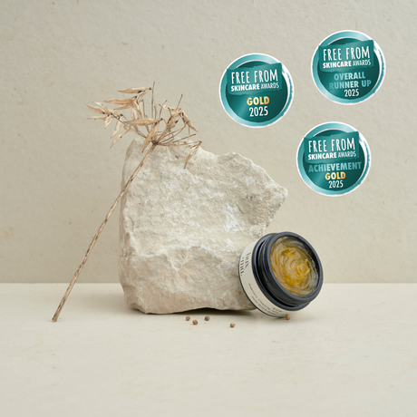 Award winning, pot of hux and mu sow prebiotic cleansing jelly leaning against a block of stone in neutral setting with strand of dried foliage. 3 award badges.