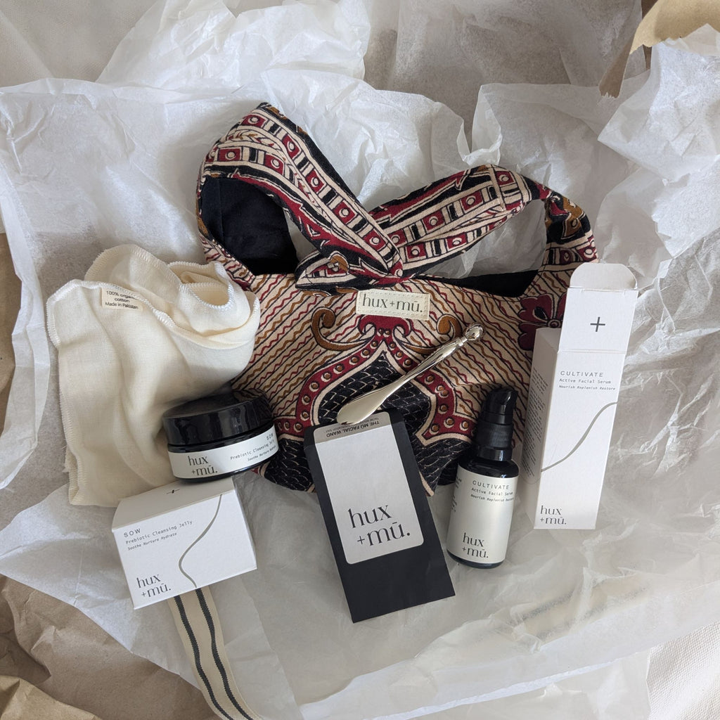 Collection of hux+mu skincare products and Indian block printed bag on crumpled paper.Perfect for gifting