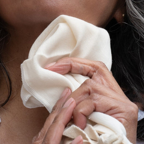 Woman holding set of three organic cotton muslins by hux and mu