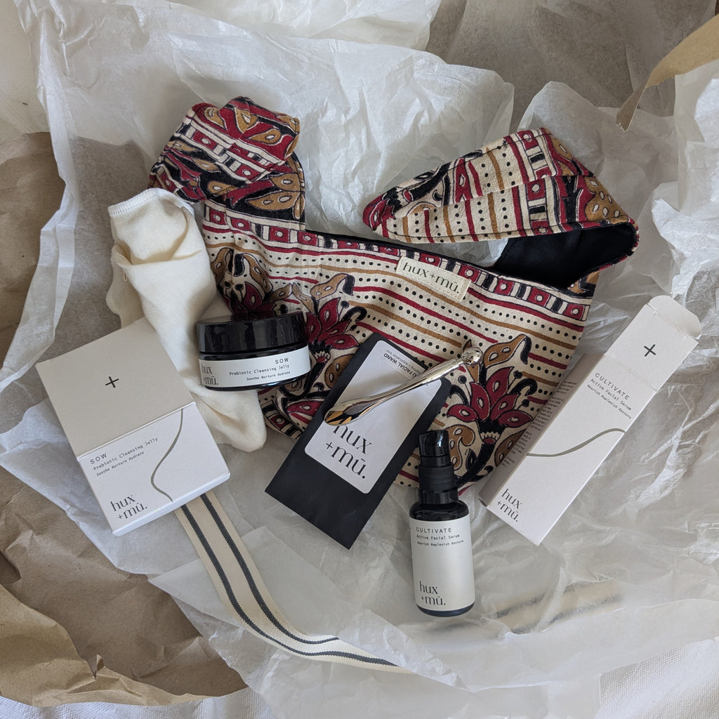 hux and mu product set with hand block printed fabric bag, skincare items, laying on tissue paper gift wrap