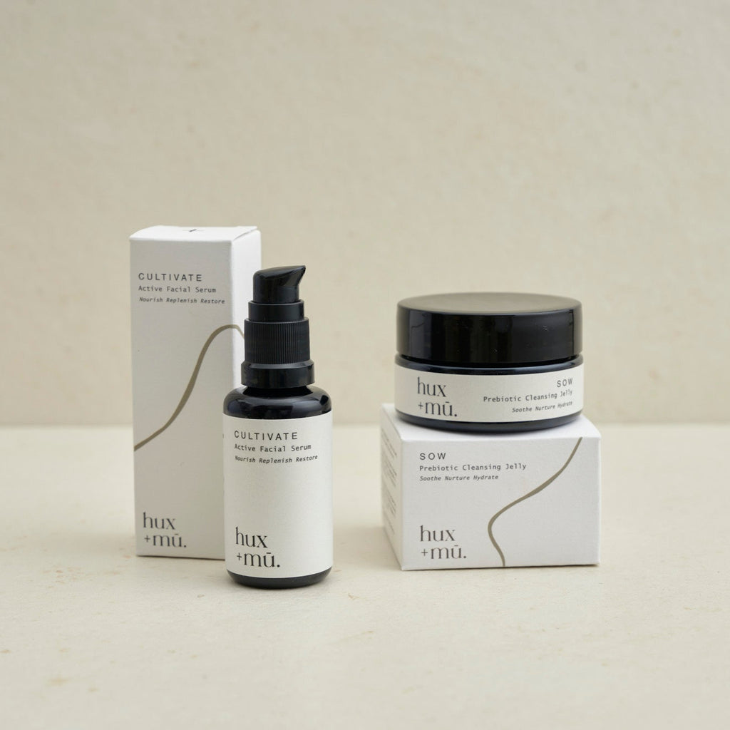 hux+mu cleansing jelly pot and facial serum bottle in neutral setting  with boxed packaging