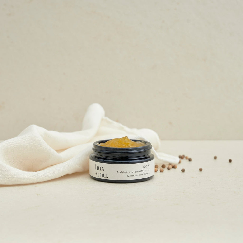 pot of hux and mu sow prebiotic cleansing jelly in neutral setting with linen face cloth and seeds